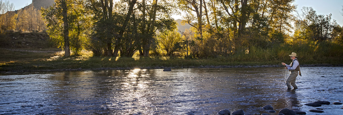 Man fly fishing in a river wearing a Rand's hat